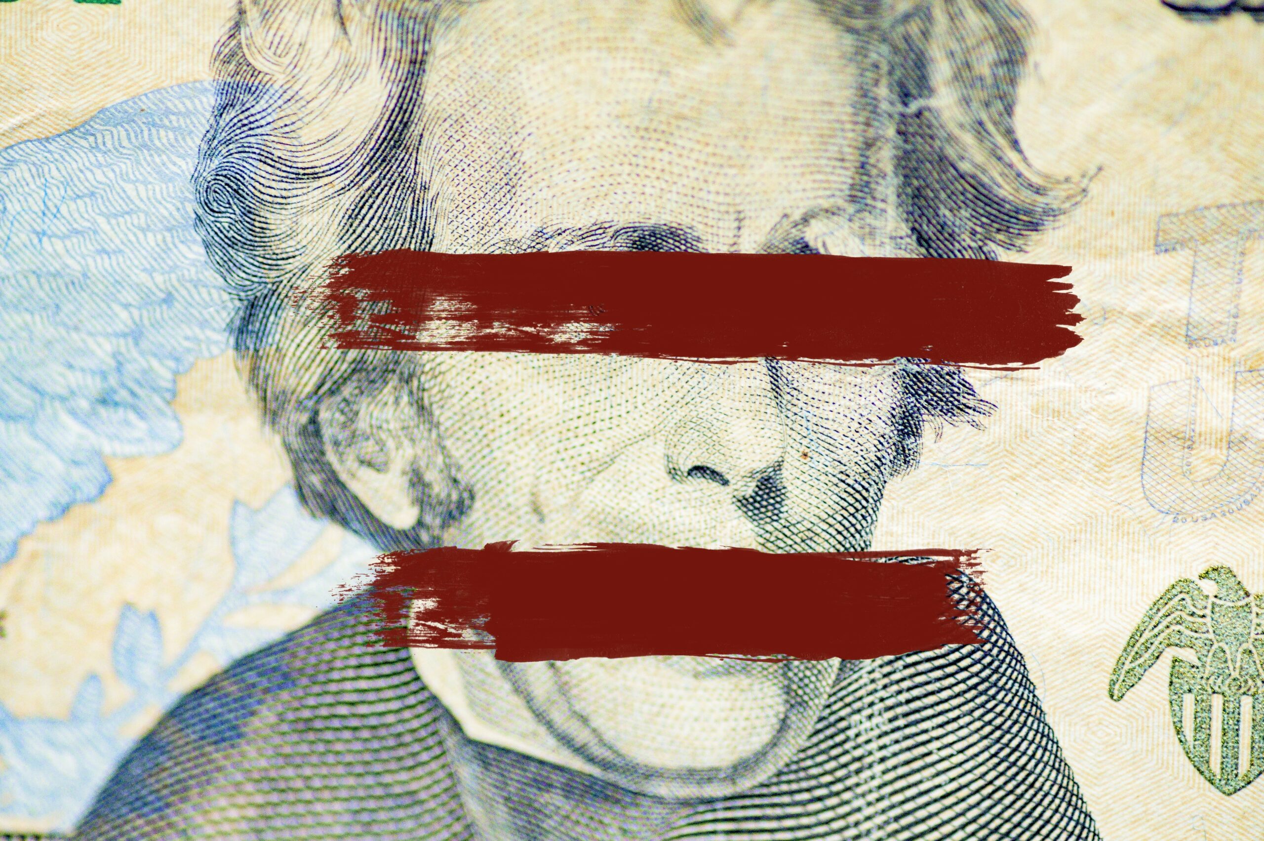 Closeup shot of the Andrew Jackson face on dollar bill with lines painted over the eyes and mouth